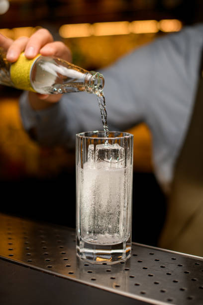 Pouring soda into a highball glass with clear ice