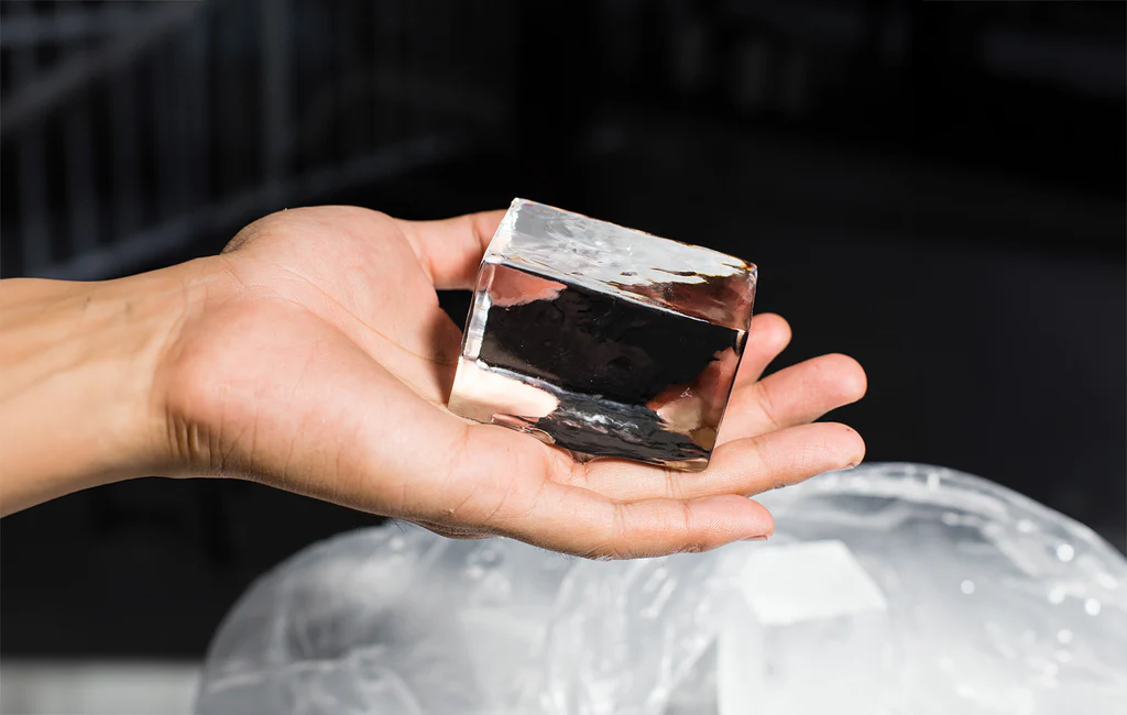 A hand holding a clear ice cube